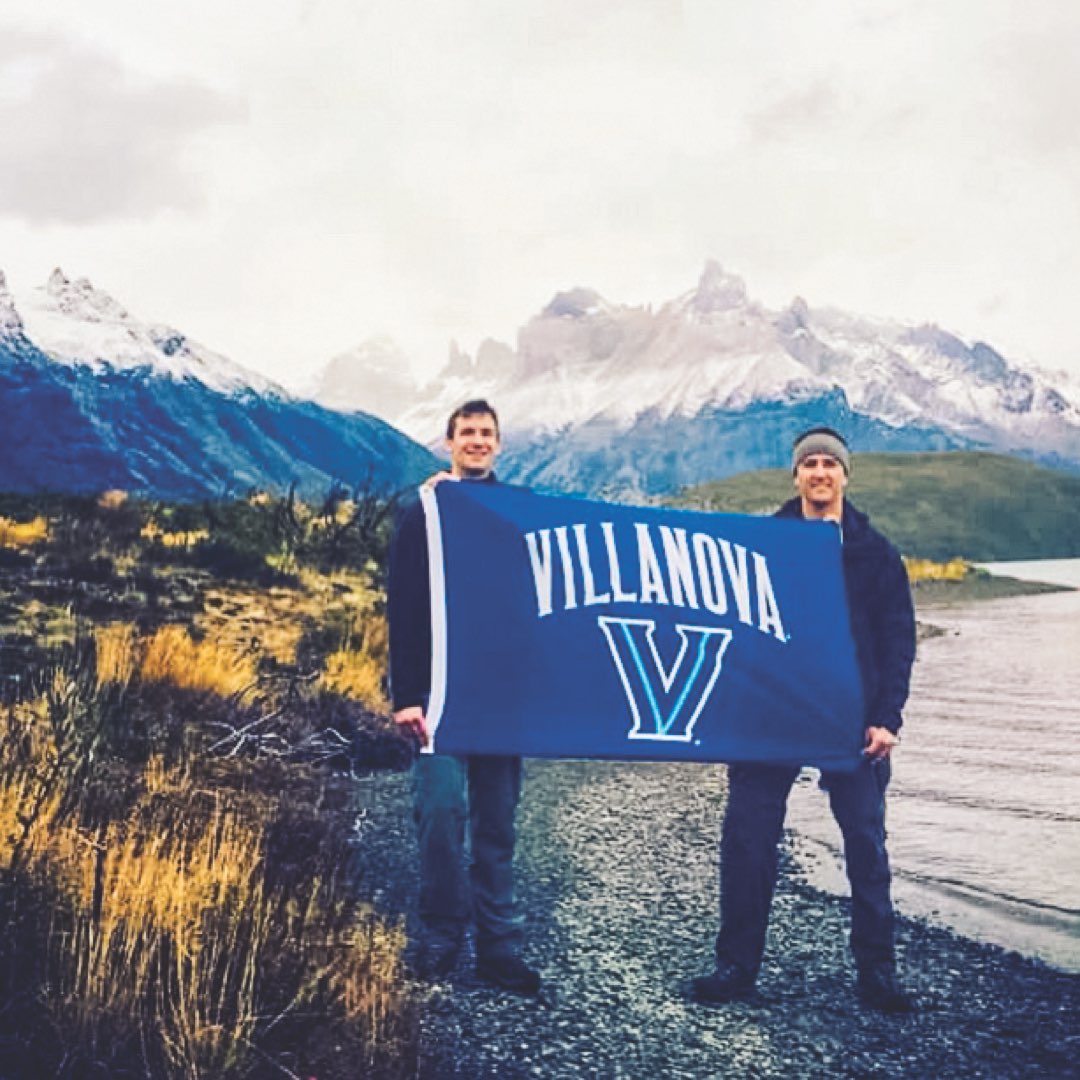 Two male Villanova alumni holding a Villanova banner in Torres del Paine National Park, Chile