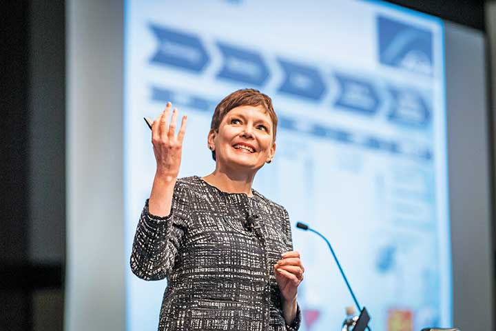 Anne Roby at a microphone giving a presentation