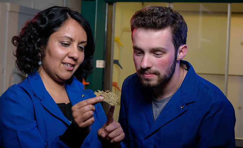 A student and professor study a piece of coral.