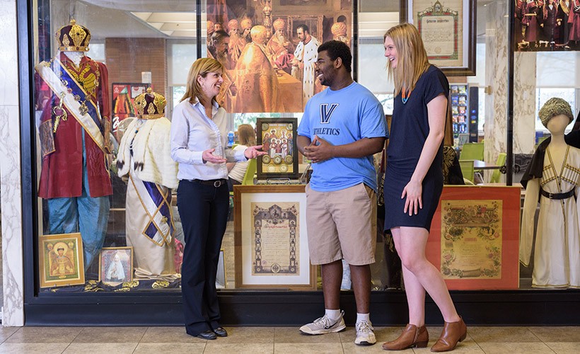 Two students and their professor look at a Russian exhibit in the library. Two students and their professor look at a Russian exhibit in the library.