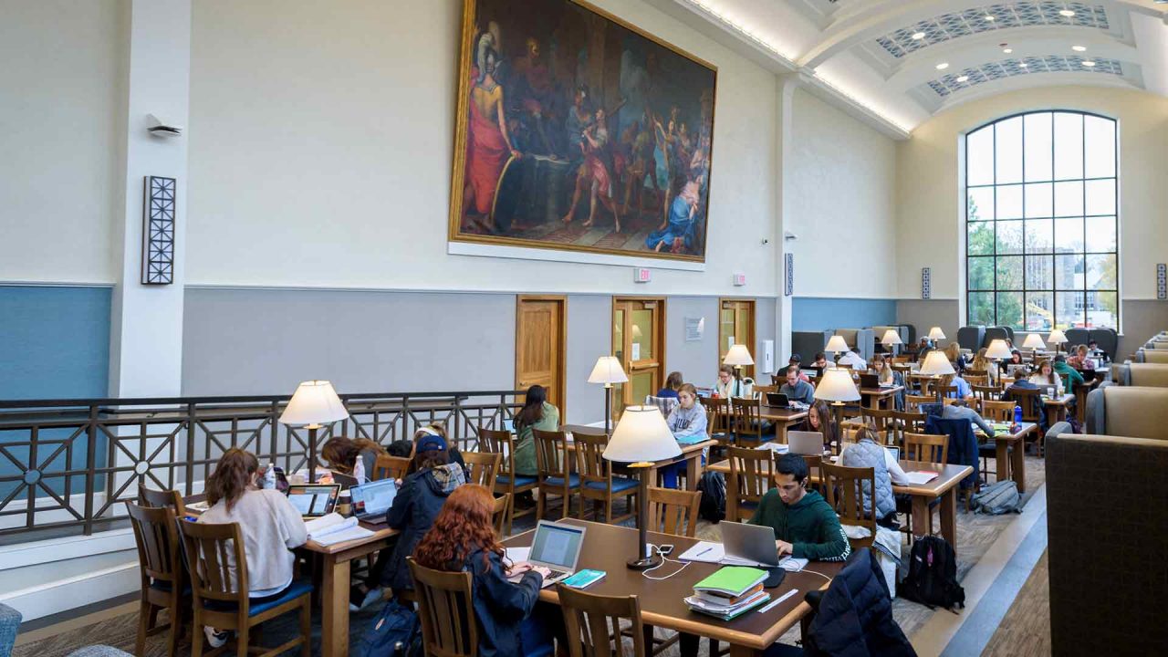 Students in the Falvey Library's Dugan Polk Family Reading Room sit at tables studying 
