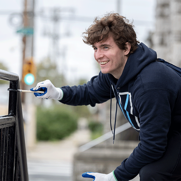 Male Villanova student paints on Day of Service