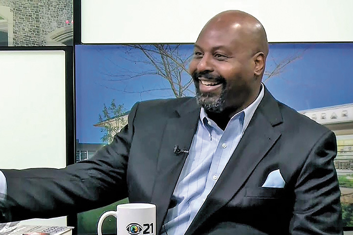 Bo-Dean Sanders sitting at a desk with a copy of his memoir